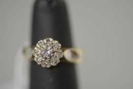 A diamond cluster ring, of flowerhead form, the centre claw-set stone within a band of smaller round