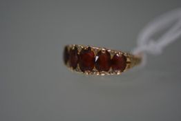 An Edwardian five stone garnet and diamond ring, the oval graduated garnets spaced by eight