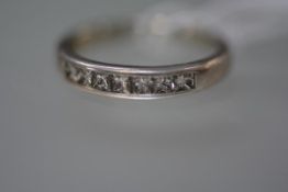 A diamond set half hoop platinum eternity ring, channel-set with seven square-cut diamonds, by