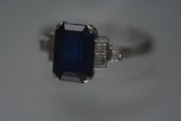 A striking sapphire and diamond ring, the central rectangular-cut sapphire weighing approximately