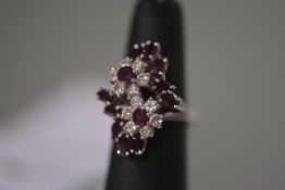 A diamond and ruby cluster ring, set with twin diamond flowerhead clusters, each with central