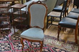 A 19th century walnut-framed nursing chair, the shell and floral carved back above a stuffed over