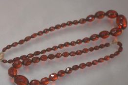 Two red amber faceted bead single strand necklaces, each of graduated oval beads. Longer 49cm, total