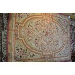 A needlework rug of Aubusson type, woven with a pattern of flowers and scrolls in shades of pink,
