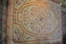 A needlework rug of Aubusson type, woven with a pattern of flowers and scrolls in shades of pink,