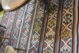 A large Kelim flatwoven rug, with horizontal, lattice and diamond bands, on a brown/terracotta