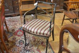 A Regency ebonised and parcel-gilt open armchair, with turned crest rail over an X-form splat, above