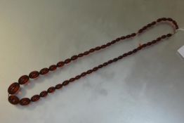 A single strand cherry amber bead necklace, the graduated oval beads on a white metal barrel