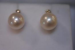 A pair of cultured pearl and diamond stud earrings, each circular pearl surmounted by a round