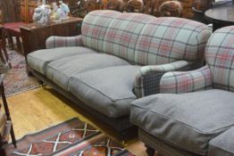 A three seater sofa, upholstered in a green tartan and tweed, with loose cushioned seat, raised on