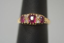 A ruby and diamond ring, early 20th century, the central cushion cut ruby flanked by a pair of