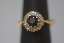 A sapphire and diamond cluster ring, the central sapphire within a band of small round brilliants,