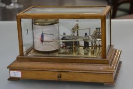 Negretti & Zambra, an oak cased barograph, the bevelled glass cover enclosing a mechanism bearing