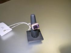 An amethyst and diamond dress ring, the large emerald-cut amethyst within a band of round