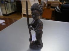 A carved hardwood figure of a standing woman, probably East African, modelled carrying a baby in a