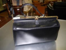 A large black handbag of Gladstone type, with gilt-brass fastener. Width 38.5cm