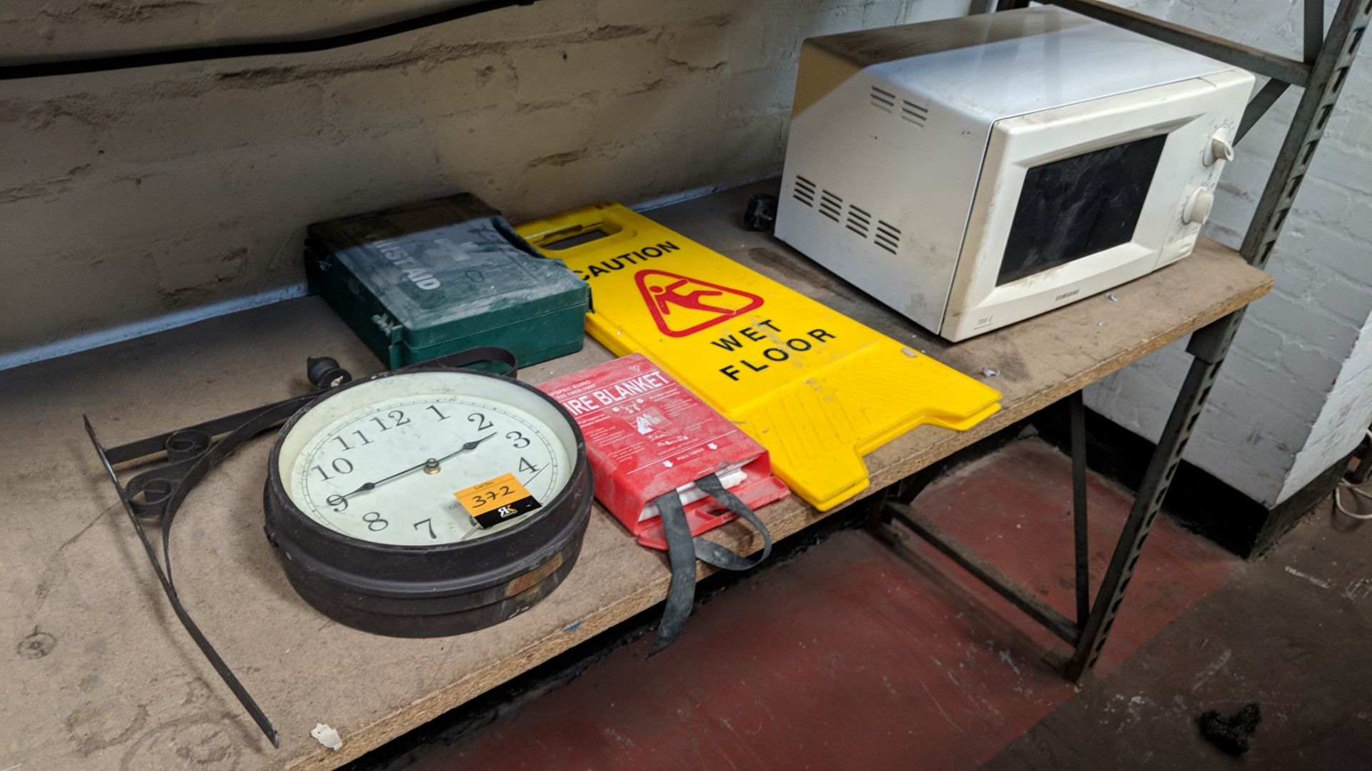 Mixed lot comprising traditional style clock plus first aid kit, fire blanket, "Wet Floor" sign