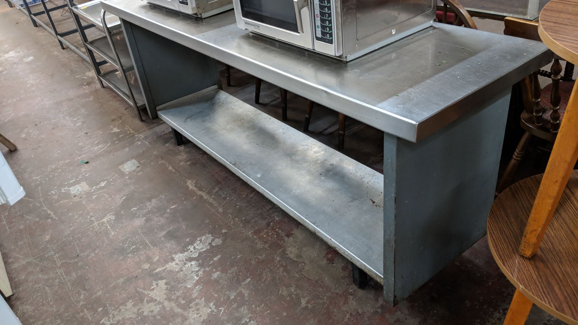 Long stainless steel twin-tier table with commercial can opener attached to same, table being