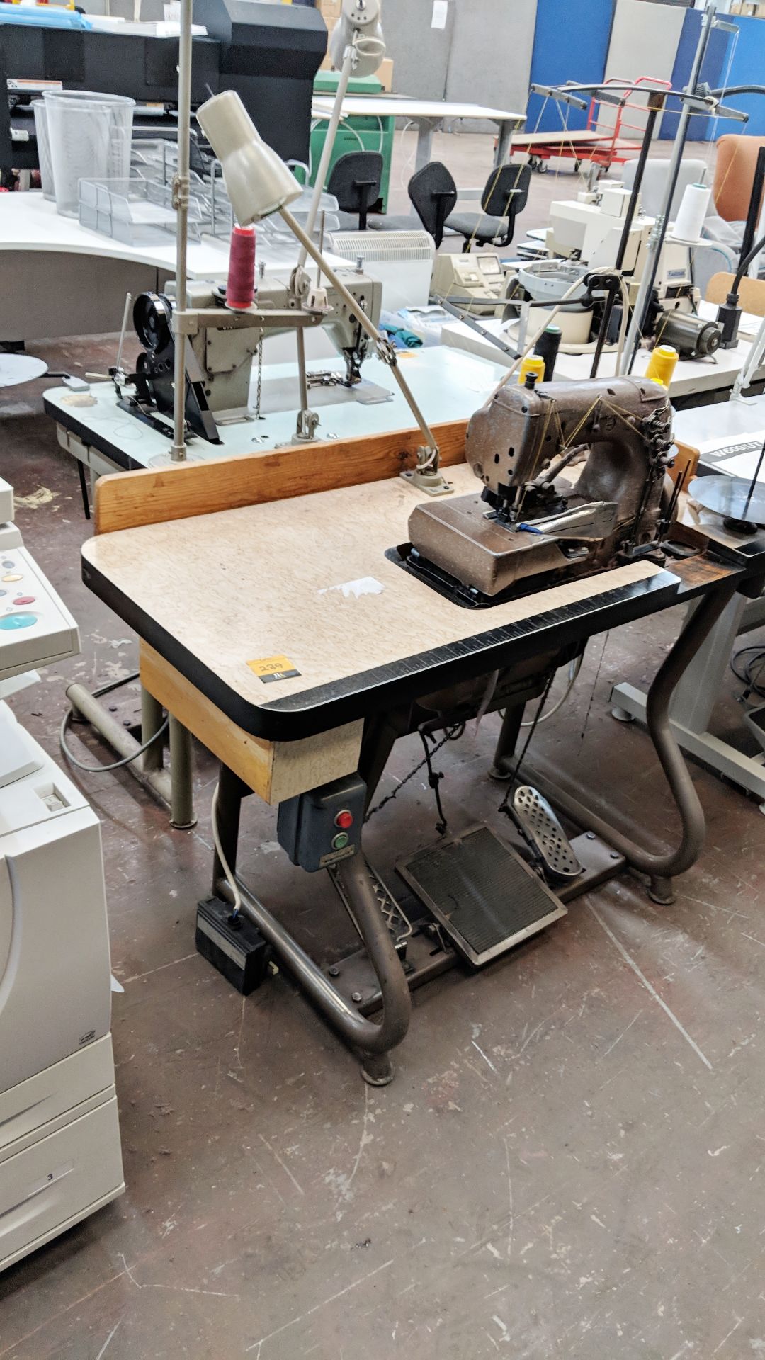 Union Special overlocker sewing machine on bench with tape feed attachments, including foot & hand