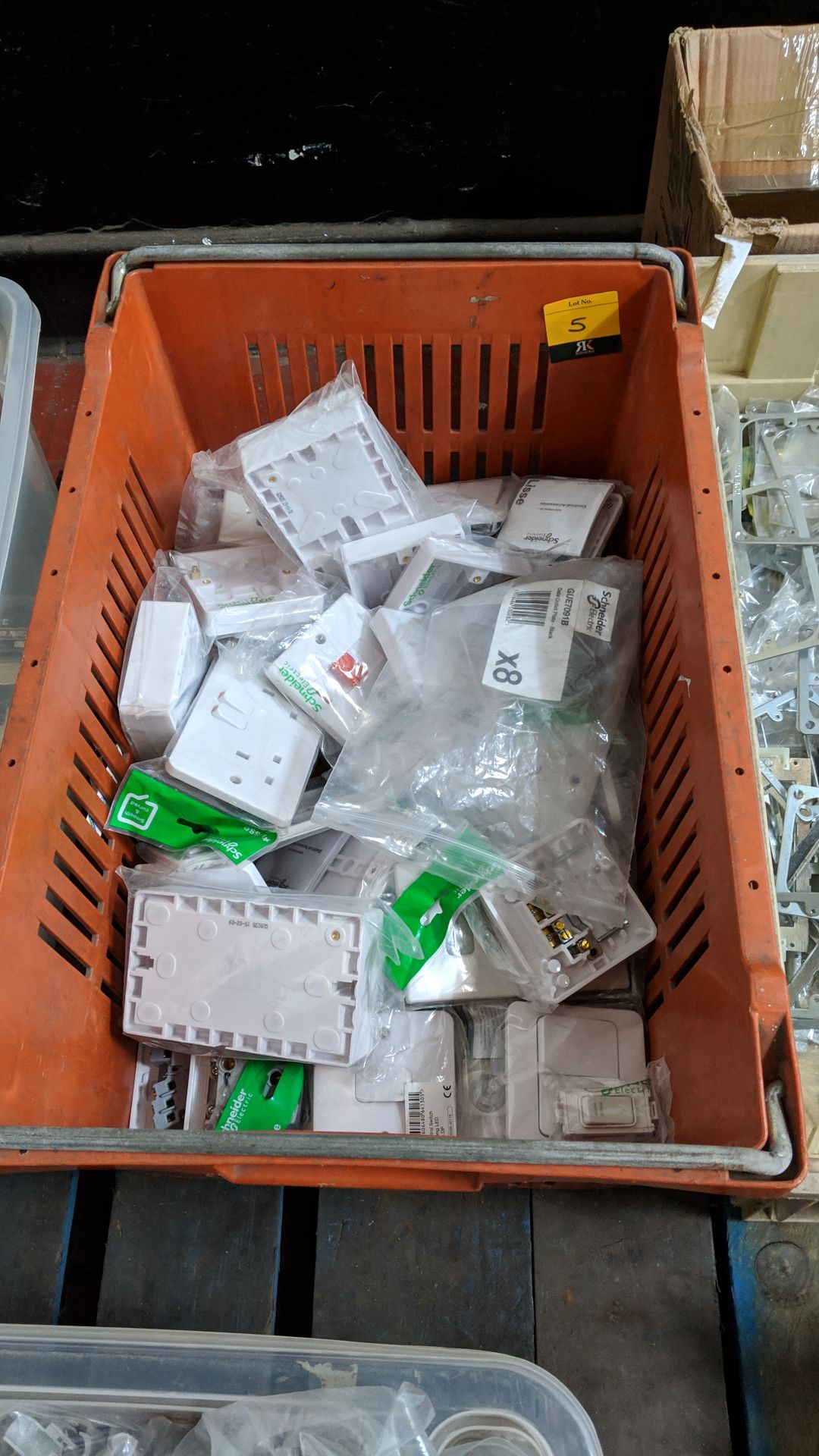 The contents of a crate of assorted Schneider white moulded plastic plug sockets, fused switches,