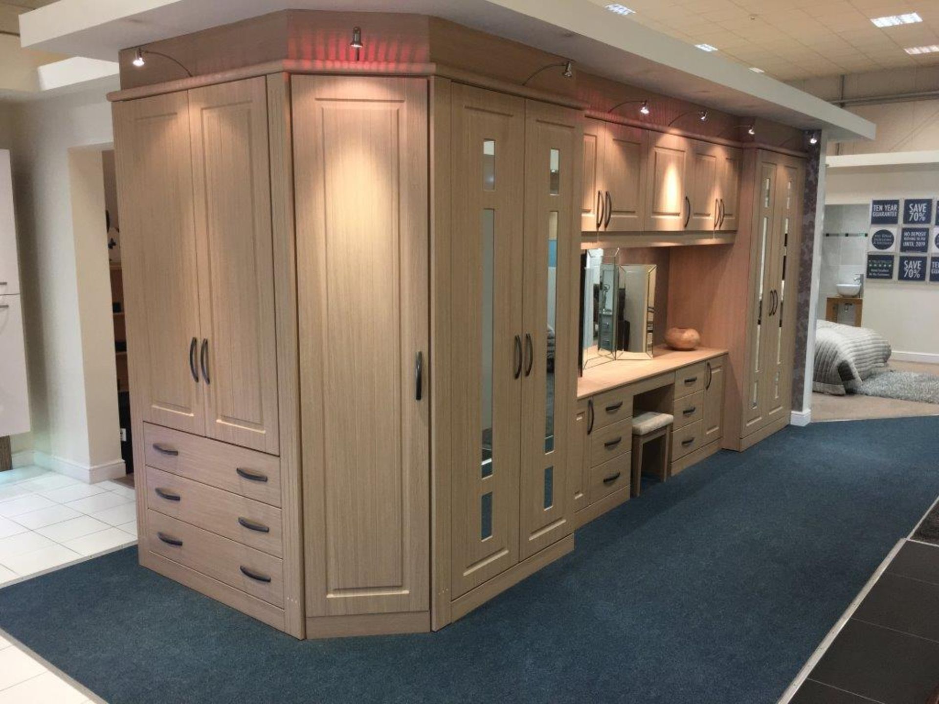 Romeo limed oak bedroom display comprising one long run of wardrobes incorporating a dressing
