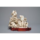 A Chinese ivory group of figures in a landscape on carved wooden base, 1st half 20th C.