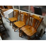 Three honey pine kitchen chairs together with a loom-style armchair