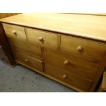 A narrow pine low chest of drawers with three short above four other drawers