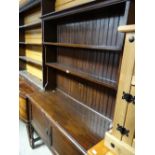 A vintage dark stained oak dresser on raised legs with two-door cupboard base & rack