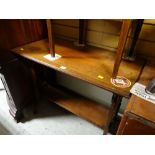 An Edwardian oak console-style table with lower shelf & on castors