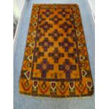 A BALUCHI WOOLLEN RUG, rust ground with cross patterned central panel and repeating running