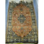 A FINE SILK QUOOM RUG having a three row border, rust ground centre with medallion and floral design