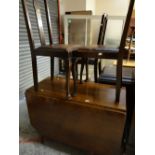 A vintage drop leaf oak dining table together with three splat back dining chairs with drop-in