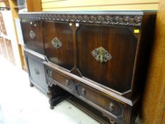 An antique reproduction dark oak raised sideboard with two cupboards above two drawers