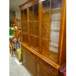 A reproduction yew wood bookcase cupboard three-door glazed top above a three drawer, three cupboard