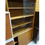 A vintage lightwood bookcase sliding glass door top above a sliding cupboard base