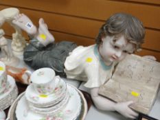 Composite figure of a young child reading a book together with two cherub ornaments
