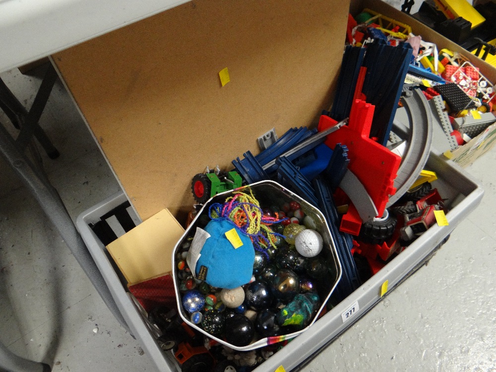 Crate of various children's plastic racing track & vehicles together with a tin of marbles