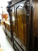 An early twentieth century oak press cupboard with three drawers & profuse carving to the side