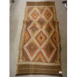 A SUZNI KILIM RUNNER, muted browns and reds in a staggered diamond pattern with tasselled ends,