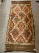 A SUZNI KILIM RUNNER, muted browns and reds in a staggered diamond pattern with tasselled ends,