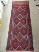 A MESHWANI RUNNER, red and blue ground with multi-pattern border and repeating centre diamond