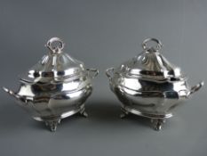 A MATCHED PAIR OF SILVER TWIN HANDLED SAUCE TUREENS and covers, of scallop form on oval bases with