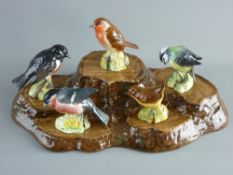 A BESWICK POTTERY GROUP OF FIVE BRITISH BIRDS on a tree stump style ceramic display stand