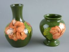 TWO MOORCROFT 'HIBISCUS' VASES of bottle and baluster form, decorated on a green ground, 12.5 and