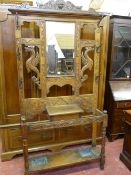 A CARVED OAK MIRRORED HALLSTAND with mask and mythical beast decoration and six double hooks,