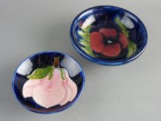 TWO MOORCROFT 'PANSY' & 'MAGNOLIA' SMALL FOOTED BOWLS decorated on cobalt blue grounds to include an