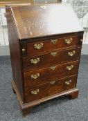 A NARROW ANTIQUE OAK BUREAU with four graduated drawers, brass furnished, pigeon-hole interior &