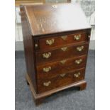 A NARROW ANTIQUE OAK BUREAU with four graduated drawers, brass furnished, pigeon-hole interior &