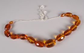 A STRAND OF FACETED & GRADUATED AMBER BEADS, fifteen beads total 14cms long